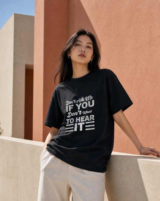 Woman wearing a black t-shirt with white text in front of a modern building.