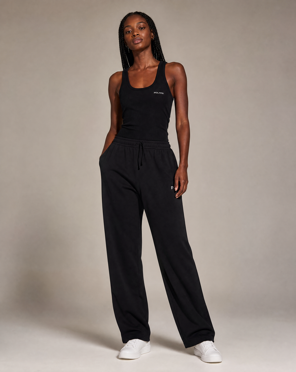A woman modeling a black sleeveless tank top and matching black wide-leg sweatpants.