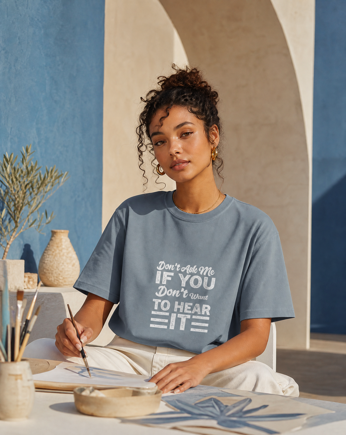 Woman wearing a blue t-shirt with text, sitting at a table outdoors.