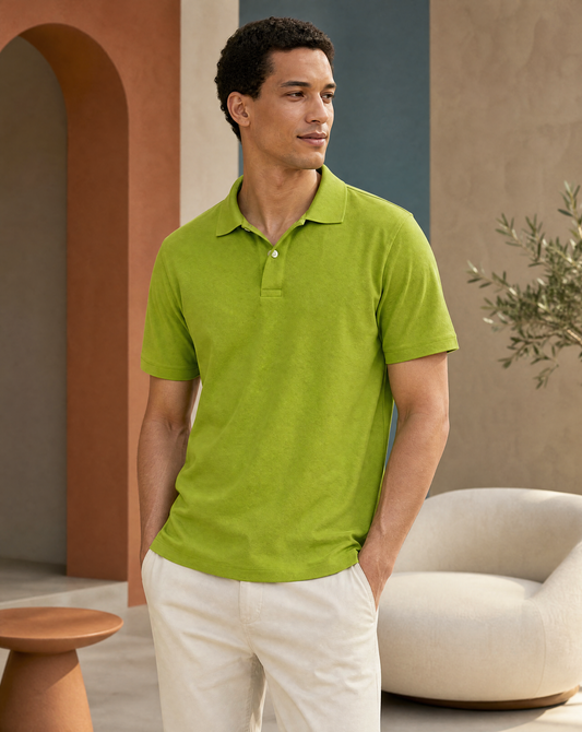 A man wearing a bright lime green short-sleeve polo shirt and off-white trousers.